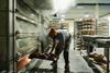 A staff member removes a tray of frshly-baked loaves out of an oven at Company Bakery's existing site in Devon Place, Edinburgh - Company Bakery