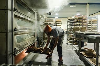 A staff member removes a tray of frshly-baked loaves out of an oven at Company Bakery's existing site in Devon Place, Edinburgh - Company Bakery