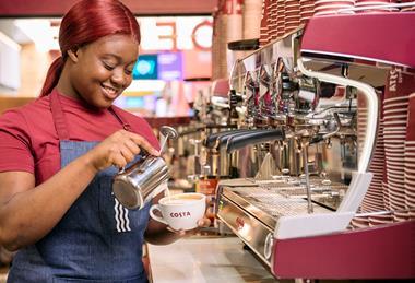 Costa employee pouring frothy milk into a mug