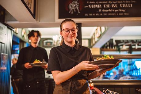 Restaurant staff carrying plated meals during busy pub dining service - stock photo