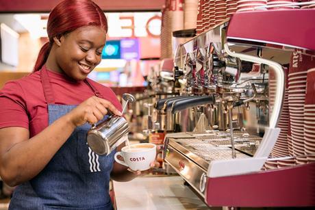 Costa employee pouring frothy milk into a mug