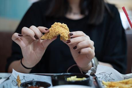 Woman eating fried chicken - Getty STOCK